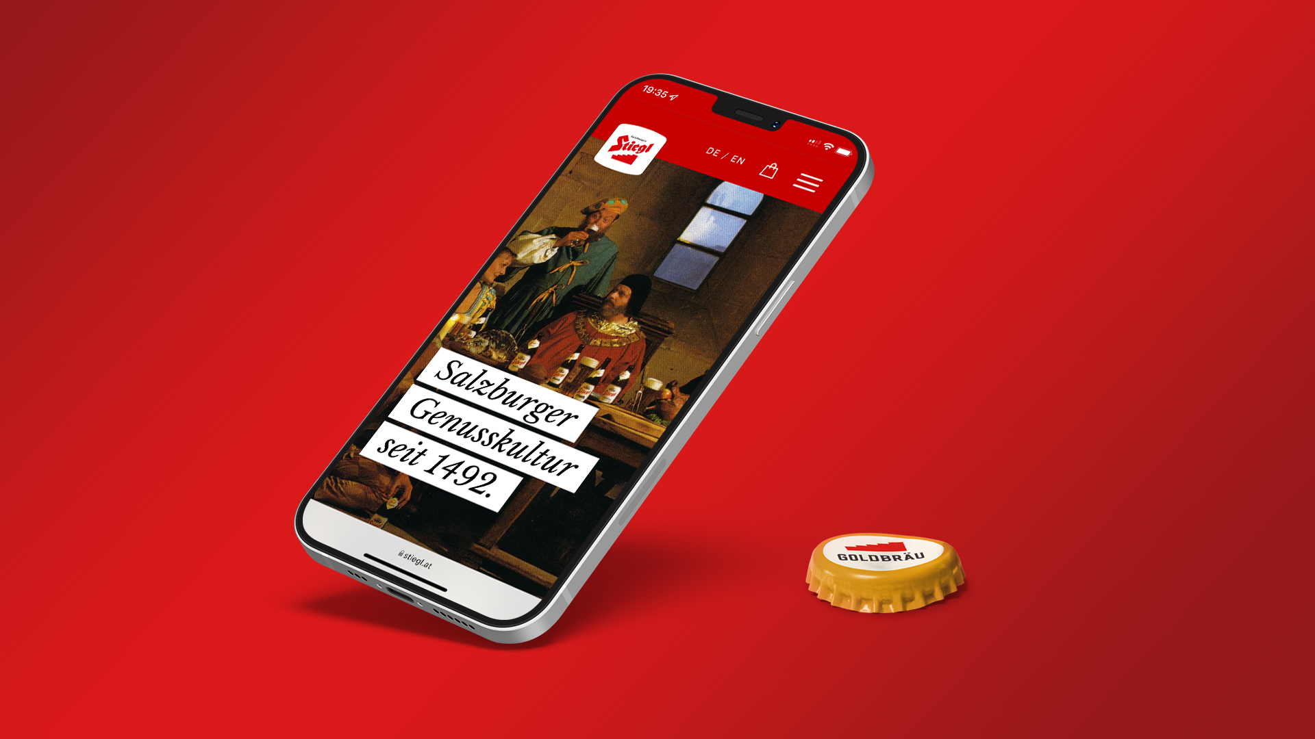 Foto von der Stiegl-Website auf einem Mobiltelefon und ein Stiegl Kronkorken daneben.