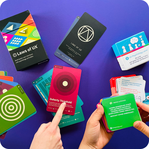 Karten für UX-Techniken liegen auf einem Tisch und Finger zeigen darauf