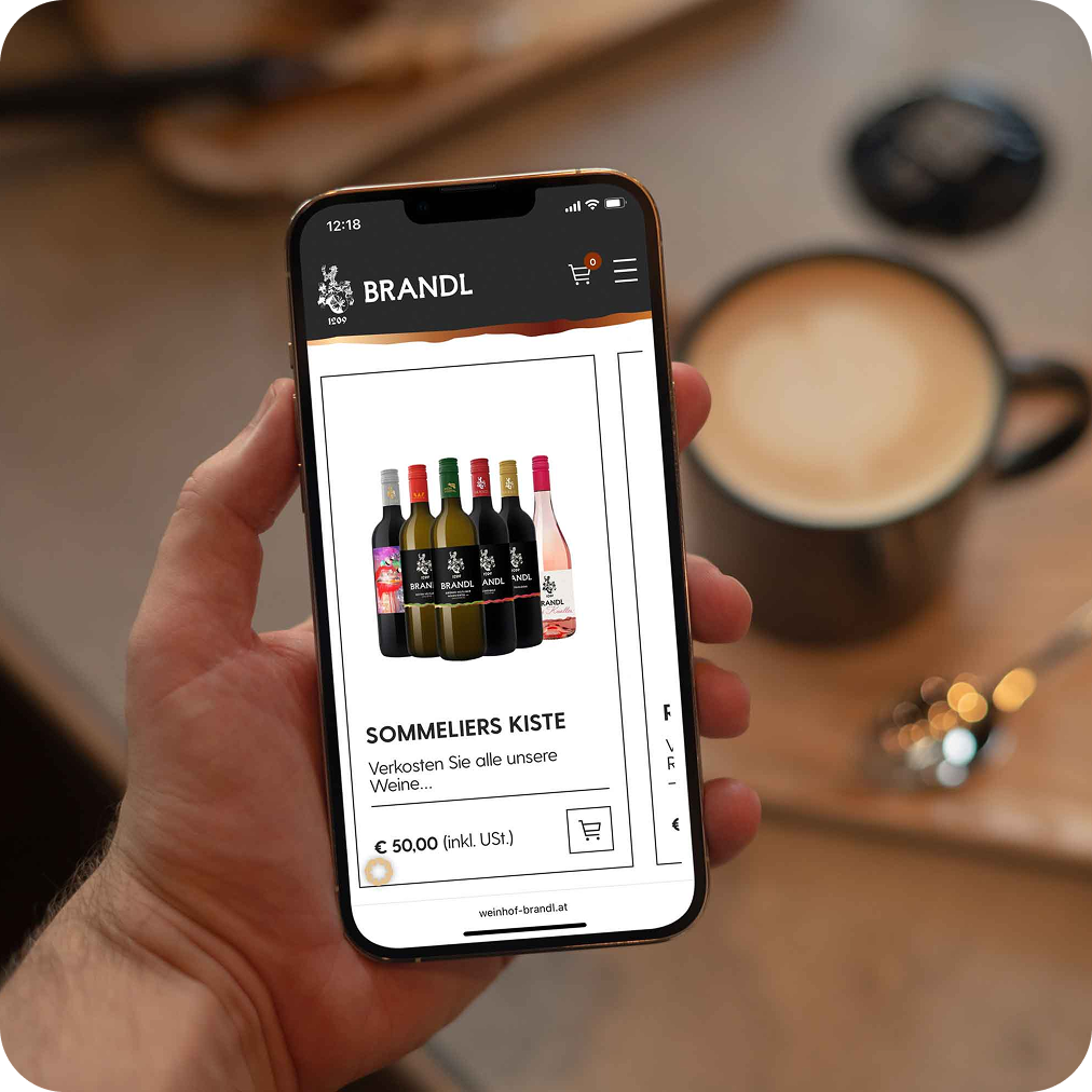 Hand hält ein Mobiltelefon, auf dem der Webshop eines Weinbauers zu sehen ist